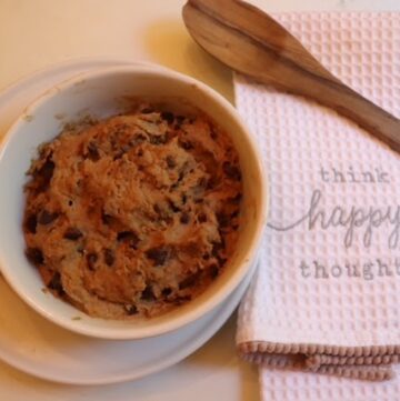 cookie dough on table with wooden spoon and tea towel