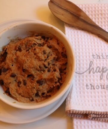 cookie dough on table with wooden spoon and tea towel